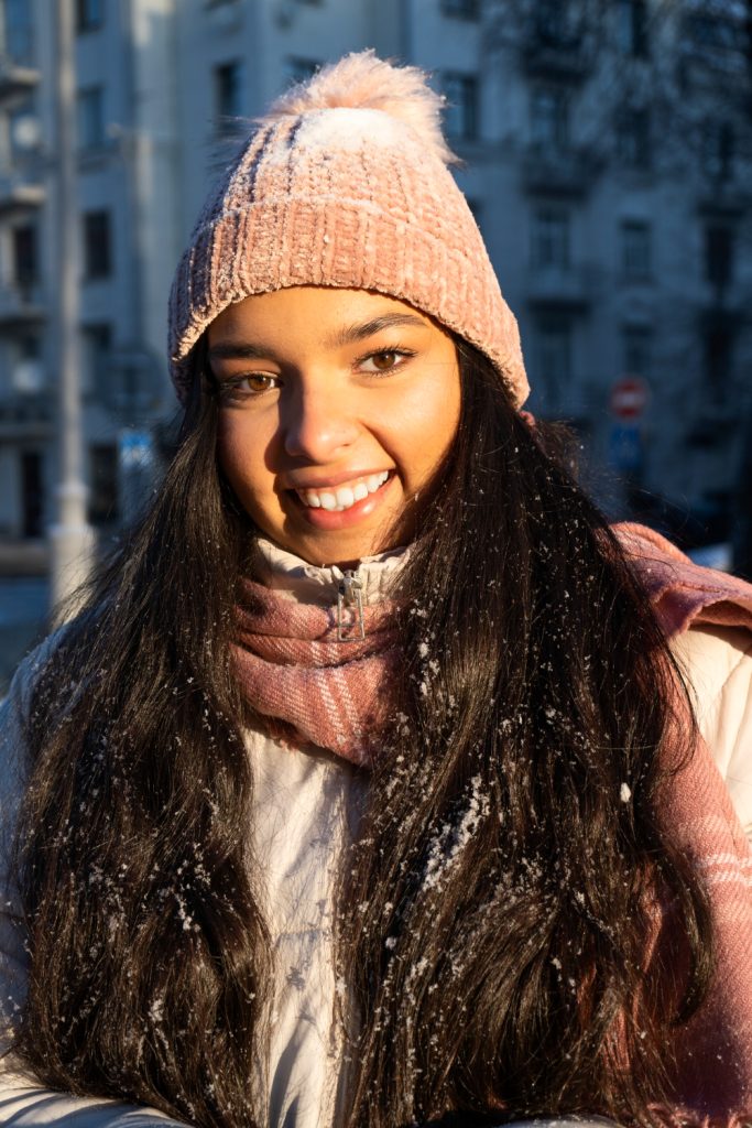 Mujer con gorro de nieve y abrigada en un entorno frío haciendo referencia al artículo de injerto capilar durante el invierno